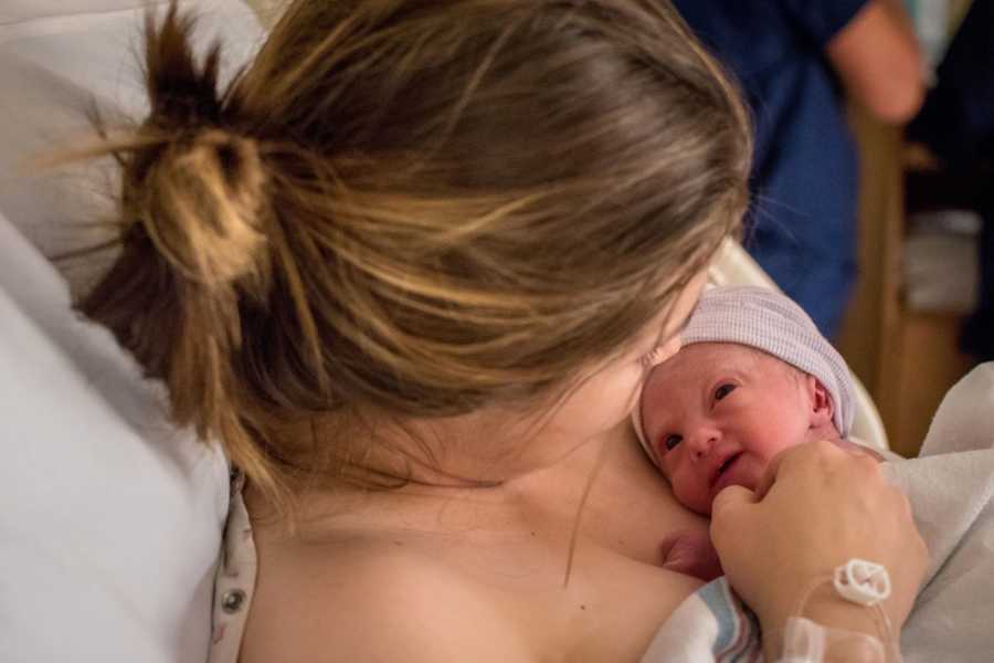 Mother looks down at newborn with Trisomy 18 that is lying on her bare chest