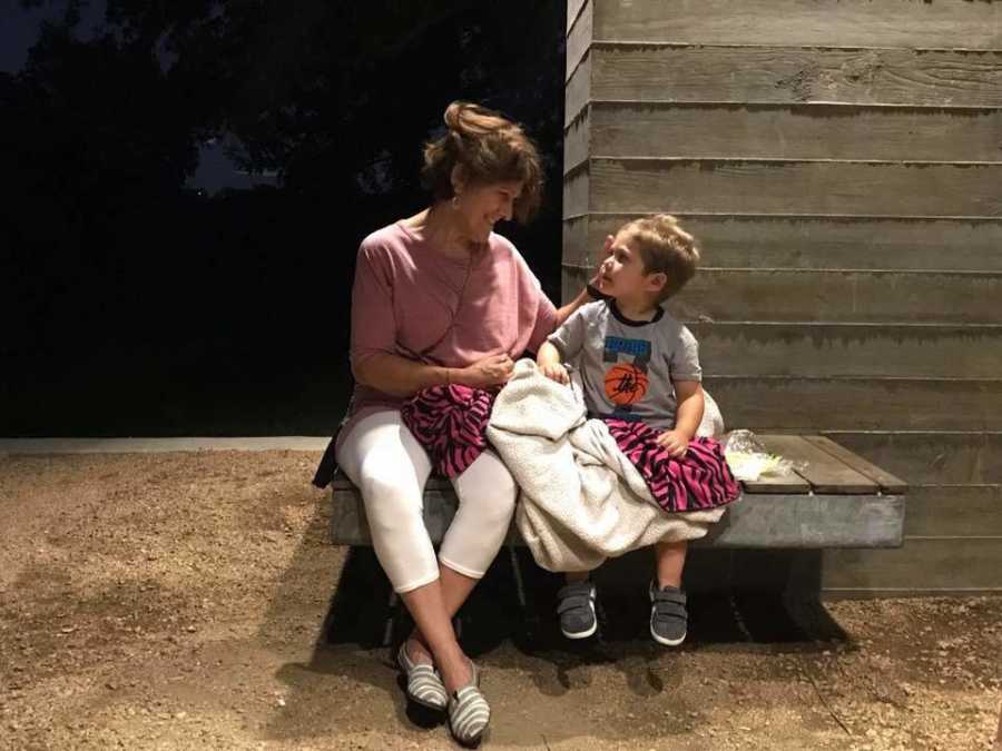 Grandmother sits smiling next to grandson on bench whose daughter taught a trick to picking him up