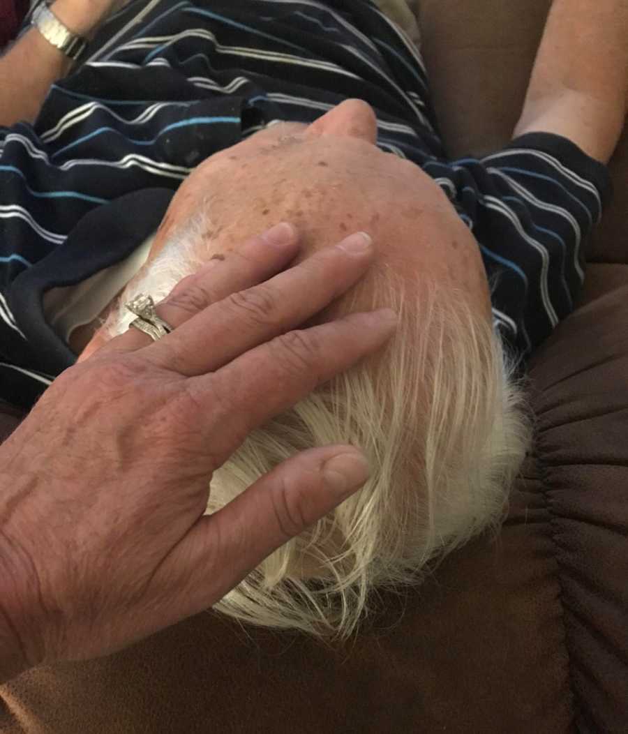 Close up of woman resting her hand on father's head who is married to woman with dementia