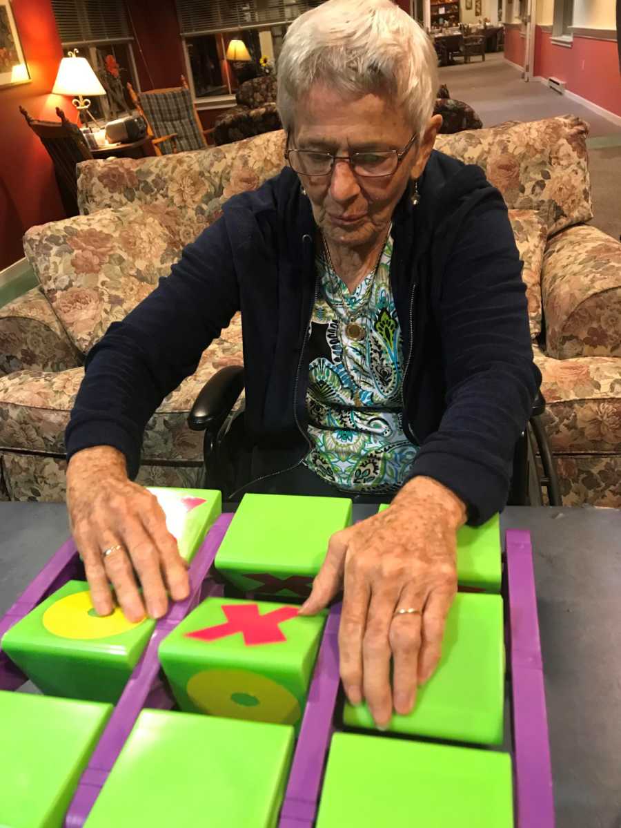 Woman with dementia sitting in nursing home playing tic tac toe