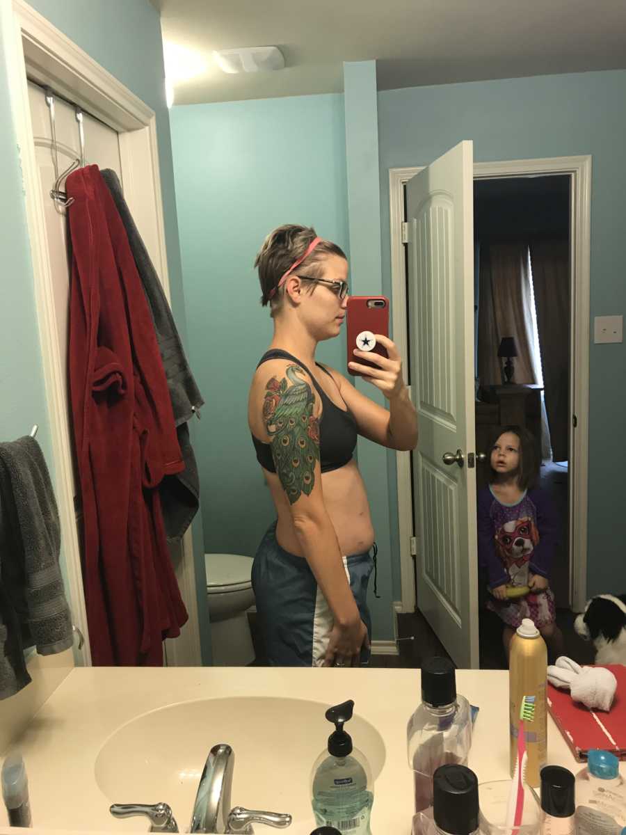 Mother takes mirror selfie of body she is ashamed of while young daughter watches in background