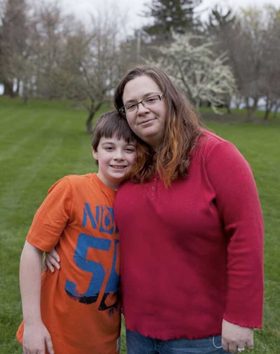 Mother who is ashamed of her weight stands smiling with son outside