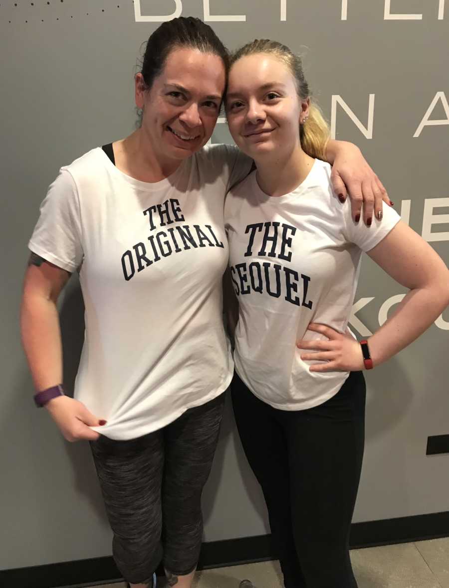 Mother stands smiling in gym wearing shirt that says, "The Original" beside daughter in shirt that says, "The Sequel"