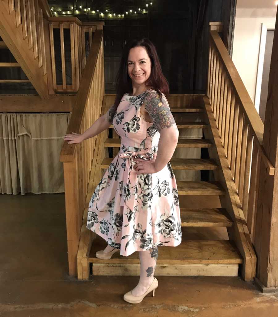 Mother who lost weight stands posing on staircase with her hand on her hip smiling