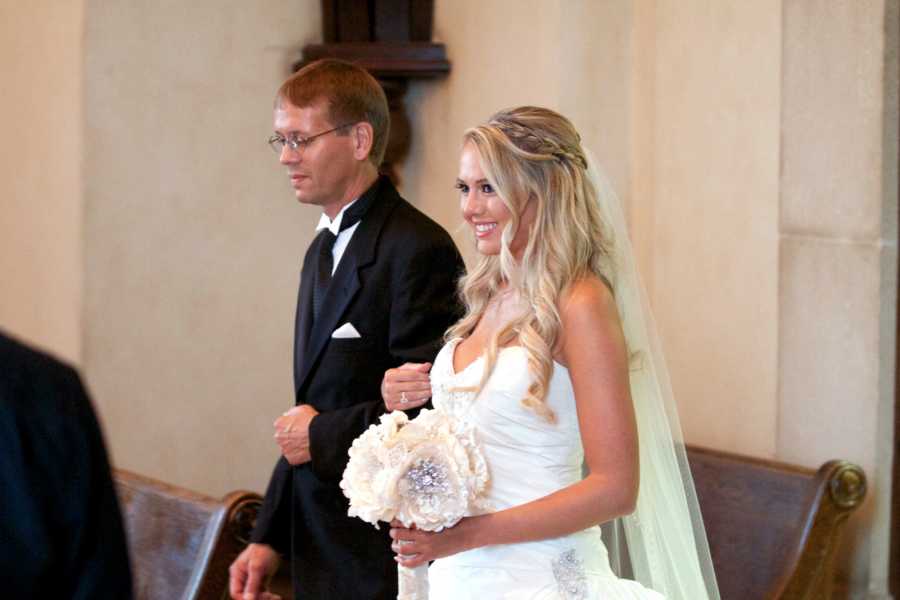 Bride smiles as she is arm in arm with father