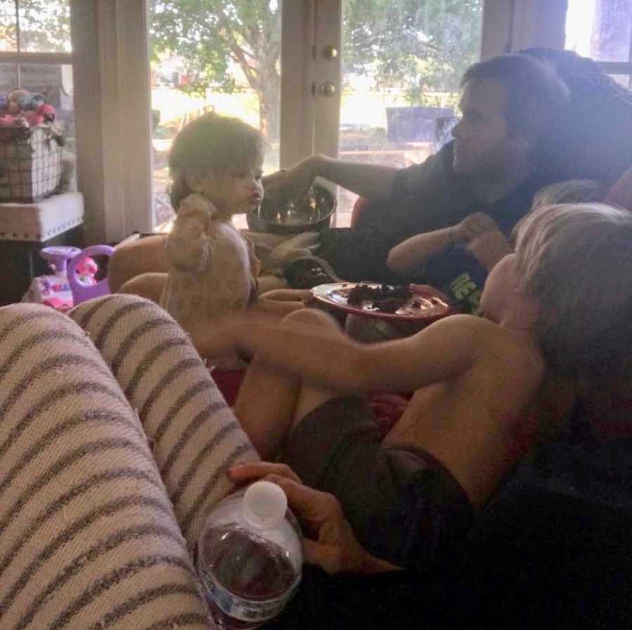 View from mother who doesn't want to miss a minute of child's lives sitting on couch with three kids and husband