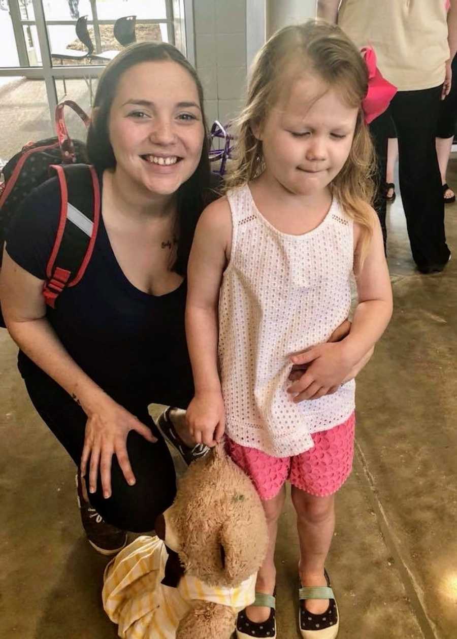 Mother who claims her autistic daughter has the best teacher crouches down smiling next to daughter