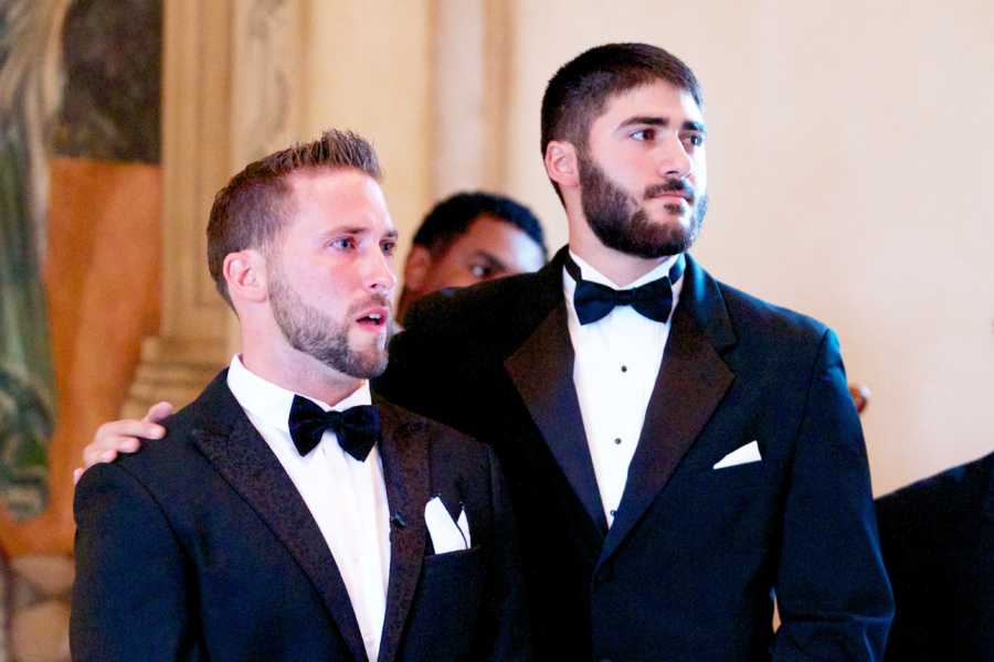 Groom stands with mouth open with best man standing beside him with hand on his shoulder