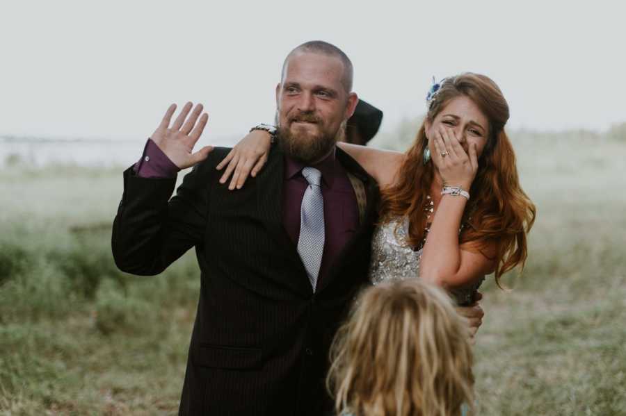 Bride and groom cry at wedding with bride's son close by