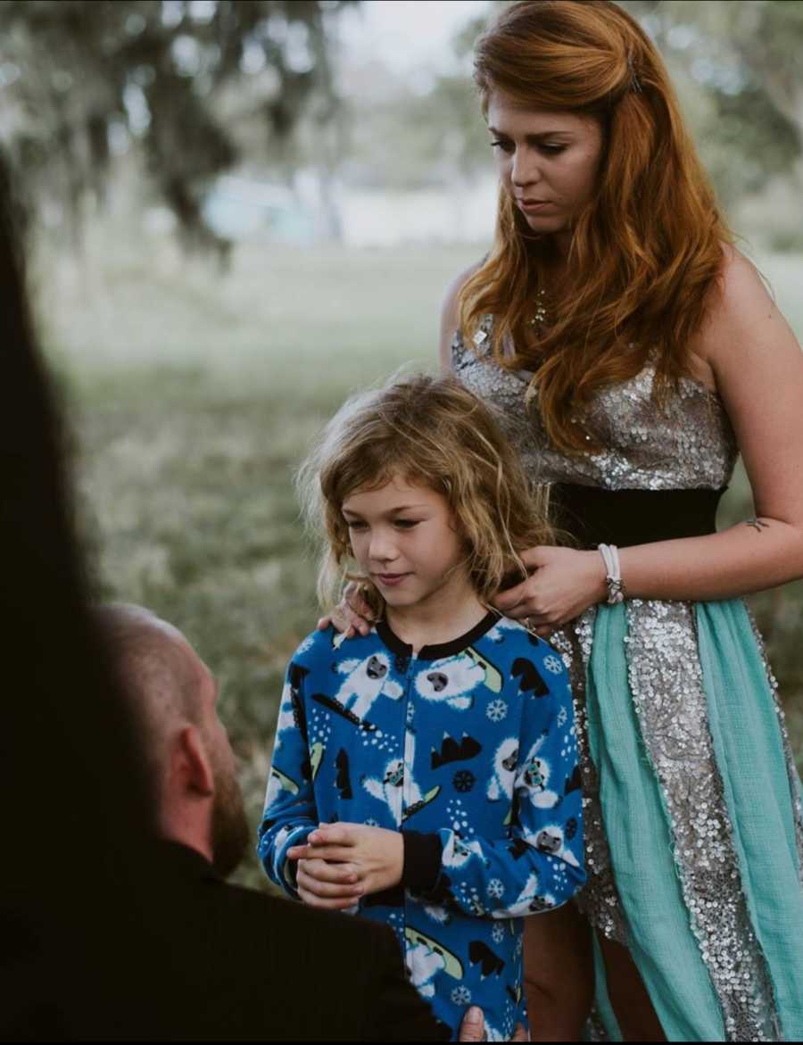 Mother standing behind son in pj's and her husband kneels in front of son