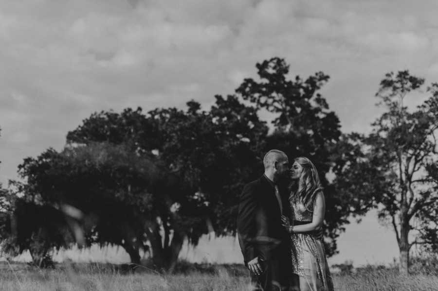 Husband and wife standing arm in arm in field