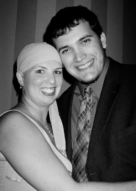 Man stands smiling next to fiancee with Hodgkin Lymphoma who has wrap around her head