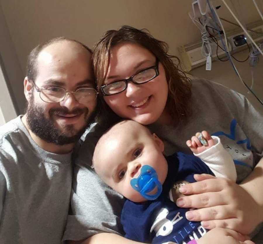 Mother and father smile in hospital with son who underwent a brain injury 