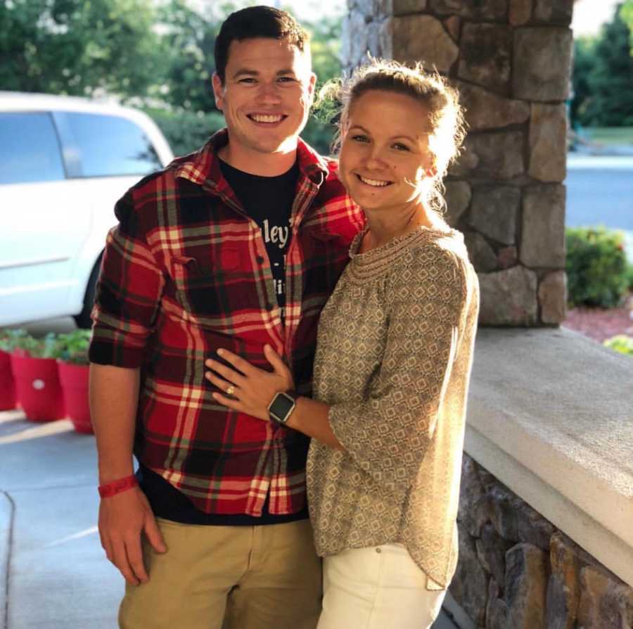 Wife who makes fun of her husband for his long bathroom breaks stands arm in arm with him smiling