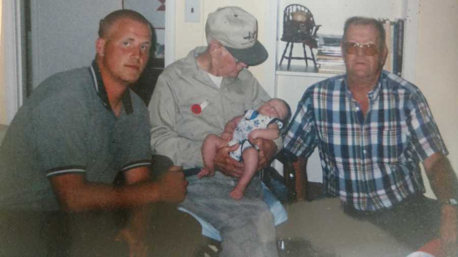 Man who was taken from parents as a child sits beside grandfather and great grandfather who holds his son