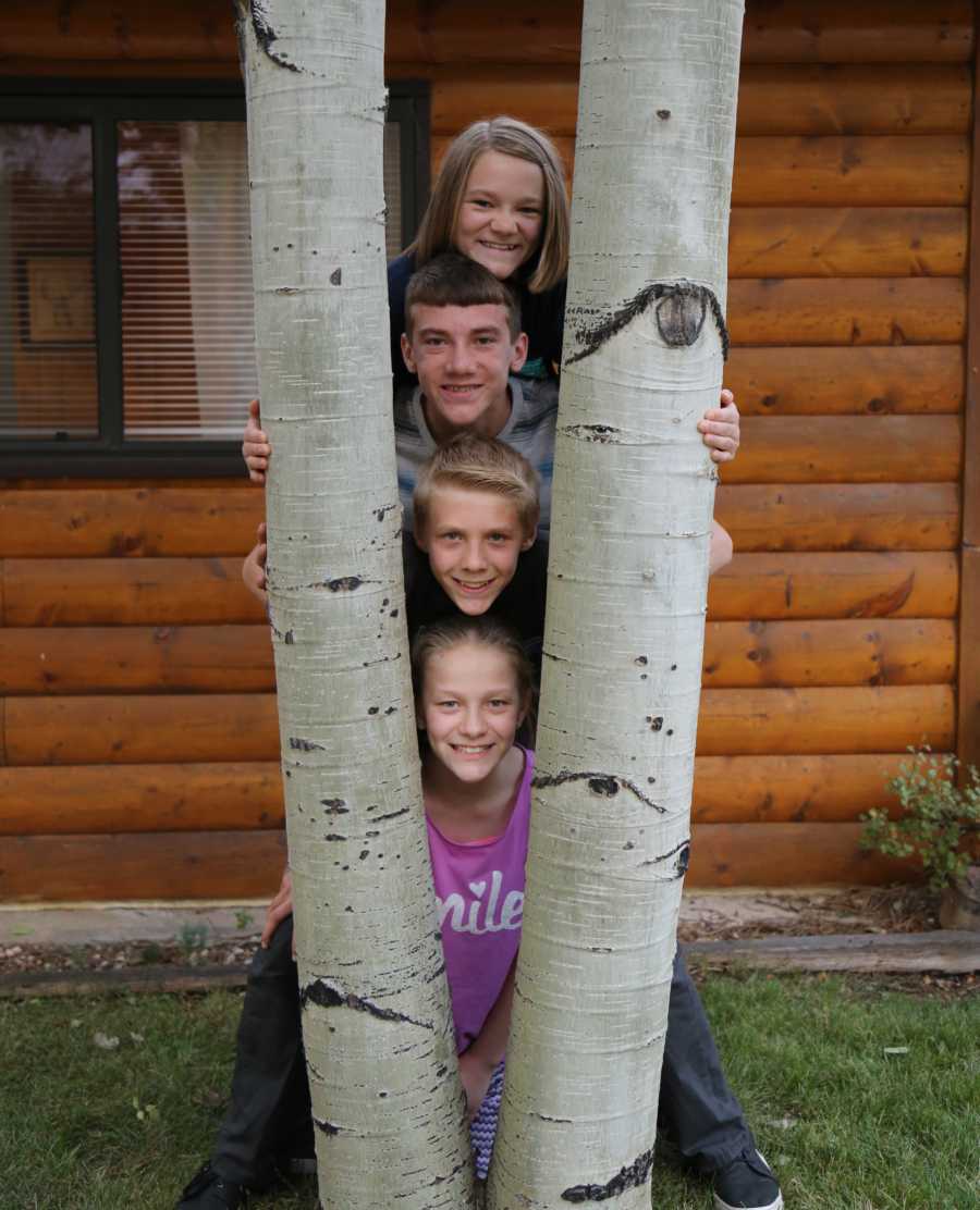 Four siblings with head popping out between trees who need foster home