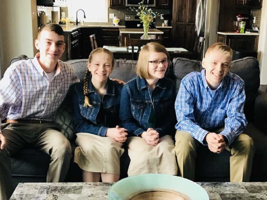 Four siblings sit on couch who were put into same foster home