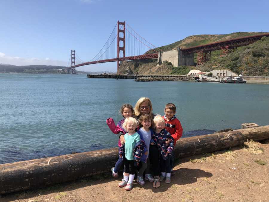 Mother who is sad her children's grandparents live far away sits with 5 kids with Golden Gate Bridge in background