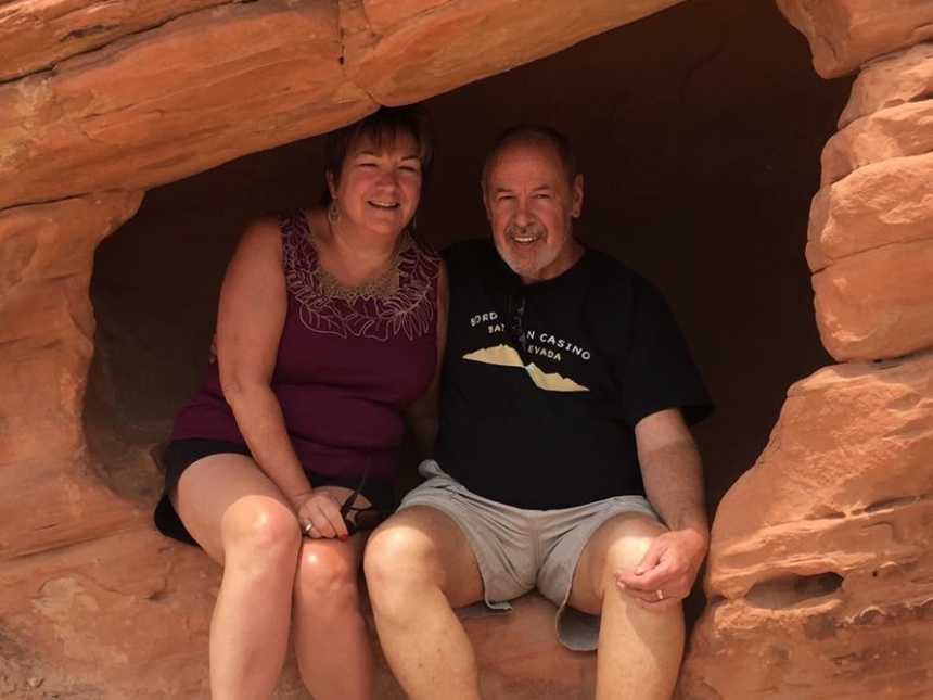 Husband and wife sitting beside each other in hole of canyon