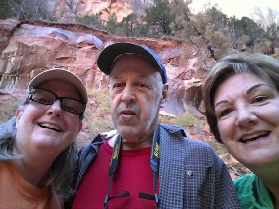 Man with cancer smiles beside wife and another woman at Red Rock