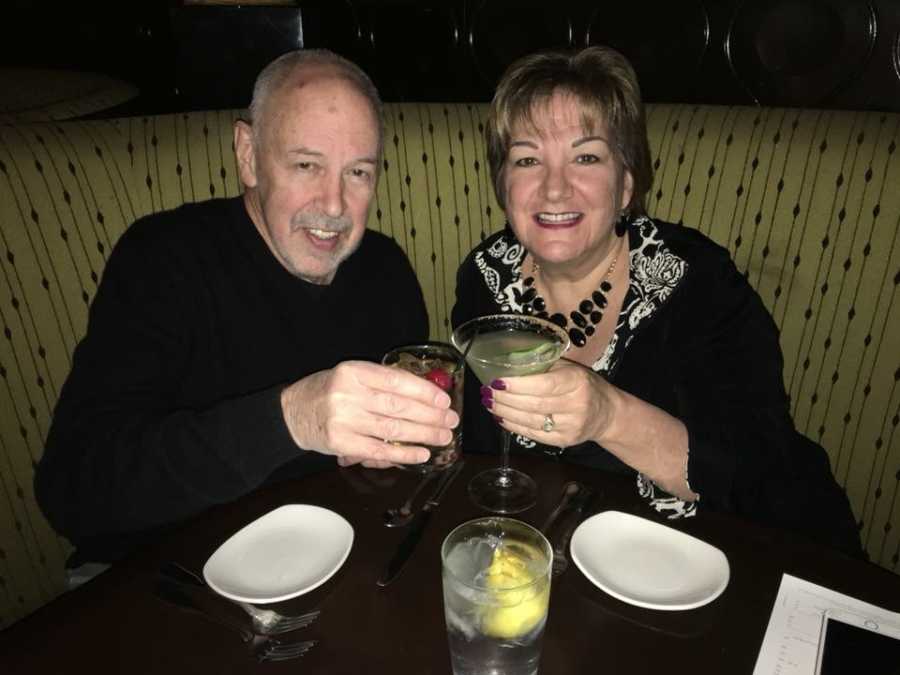 Wife smiles at restaurant while raising glass with husband who had bladder cancer