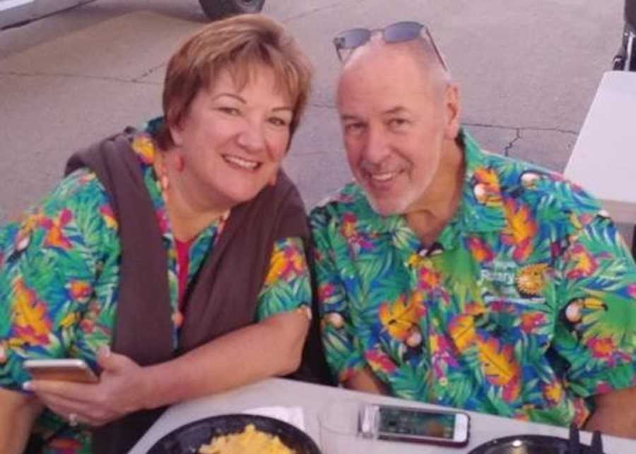 Husband and wife sitting at table in matching Hawaiian shirts