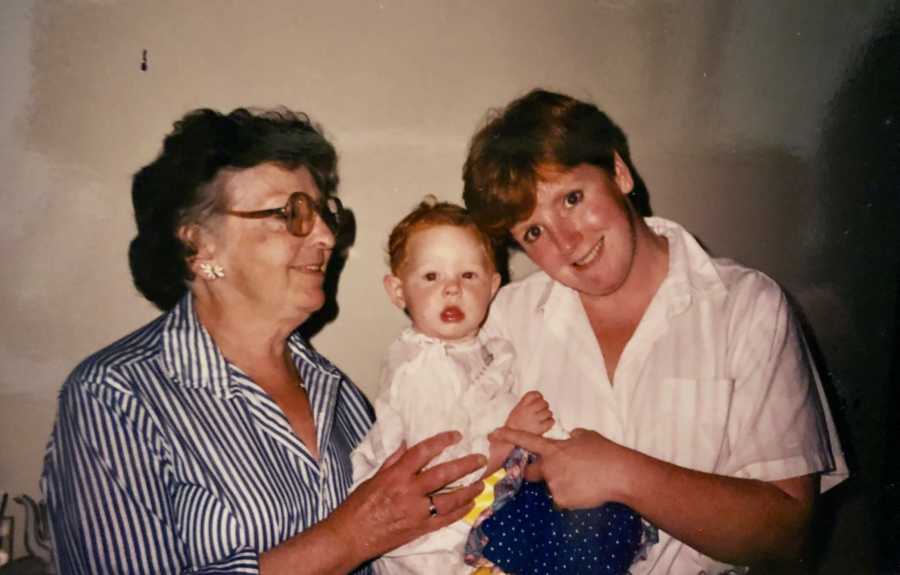 Elderly woman smile with hand on baby being held by mother