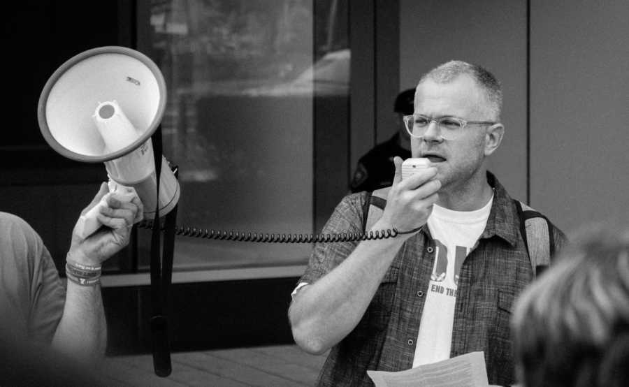 Man who was a junkie and is now an activist speaks into speaker attached to megaphone