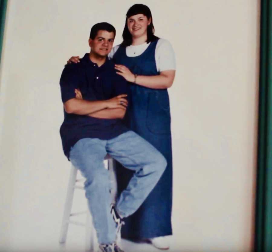 Husband sitting on stool while wife stands beside him with her hands on his shoulders