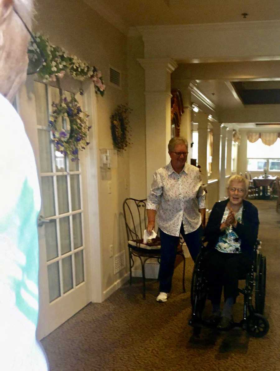 Elderly woman with dementia sits in wheelchair holding hands together as she sees her husband