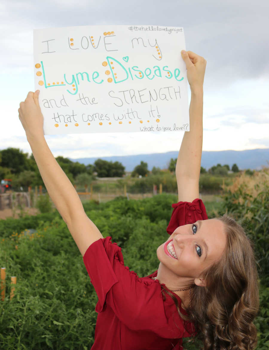 Teen smiles while holding up sign that says, "I love my lyme disease and the strength that comes with it"