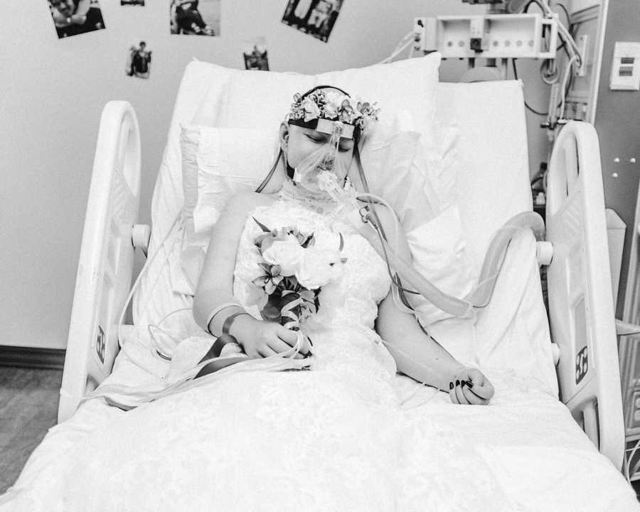 Teen with cancer sits in hospital bed wearing wedding gown and holding bouquet of flowers