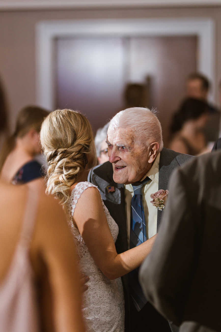 Grandfather smiles granddaughter close as they dance at her wedding