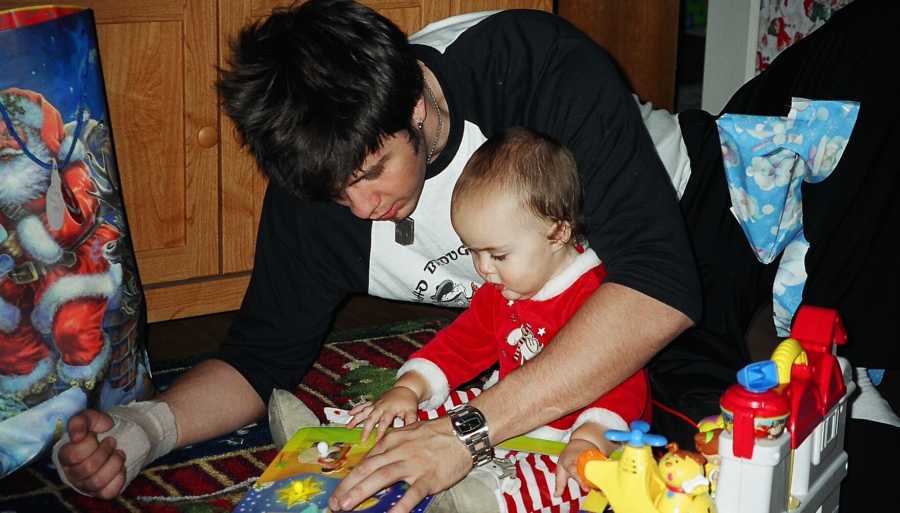 Single father lying on floor with baby daughter on Christmas morning playing with toys