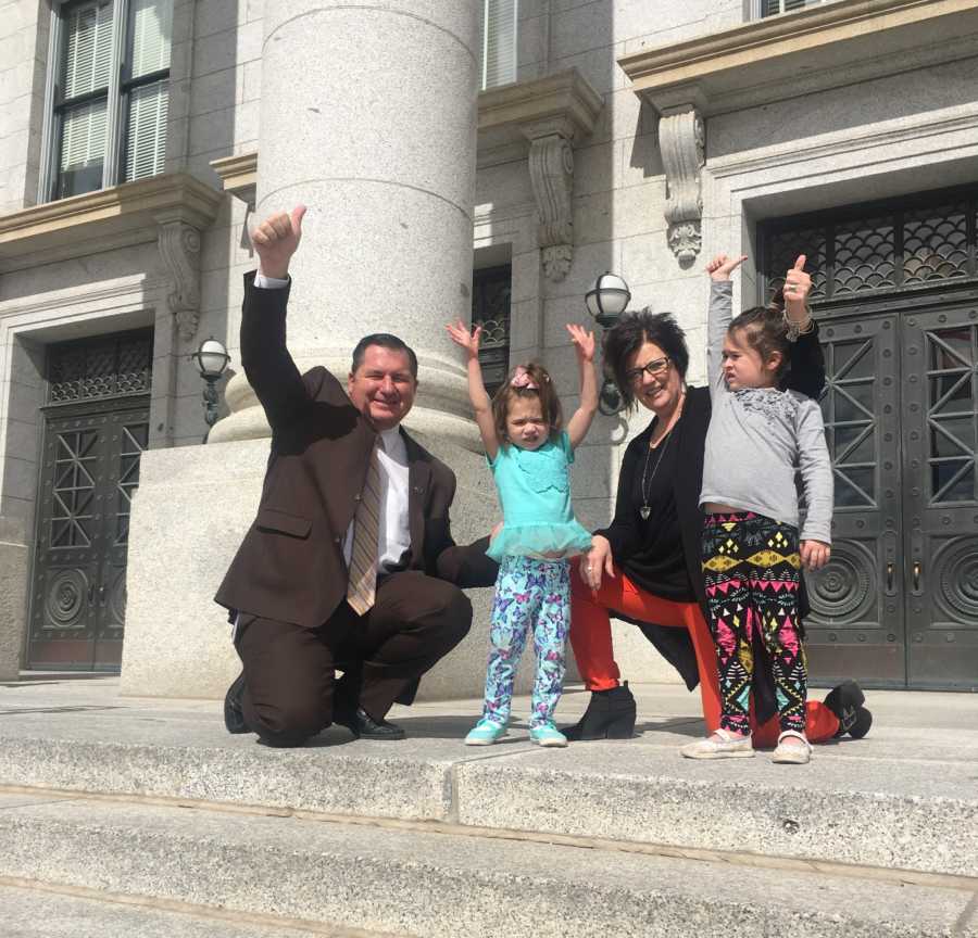 Mother standing with two daughters beside state representative to instate child abuse registry