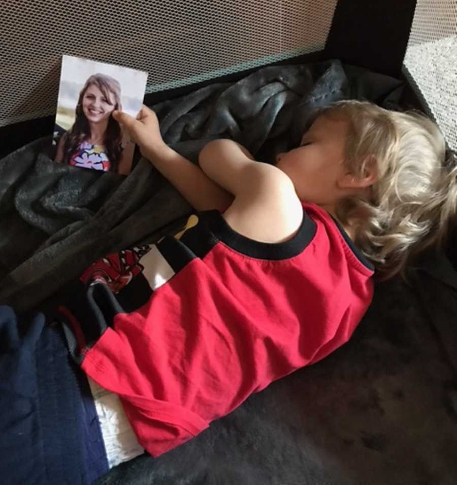 Toddler sleeps in pack and play holding picture of mother who died from Cardiac Sarcoidosis