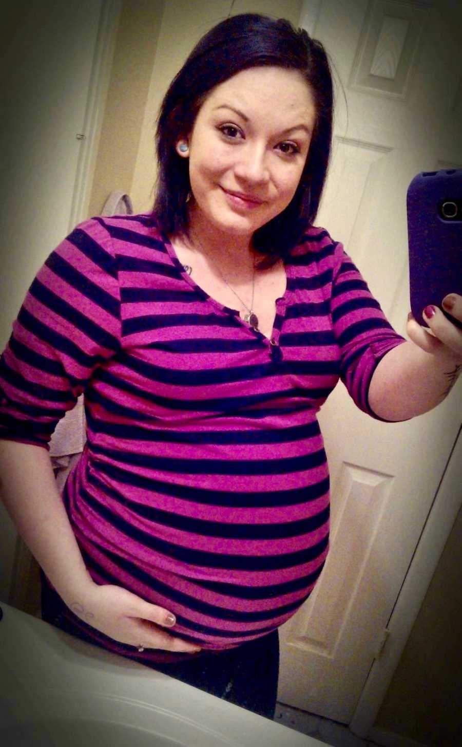 Pregnant woman smiles in mirror selfie
