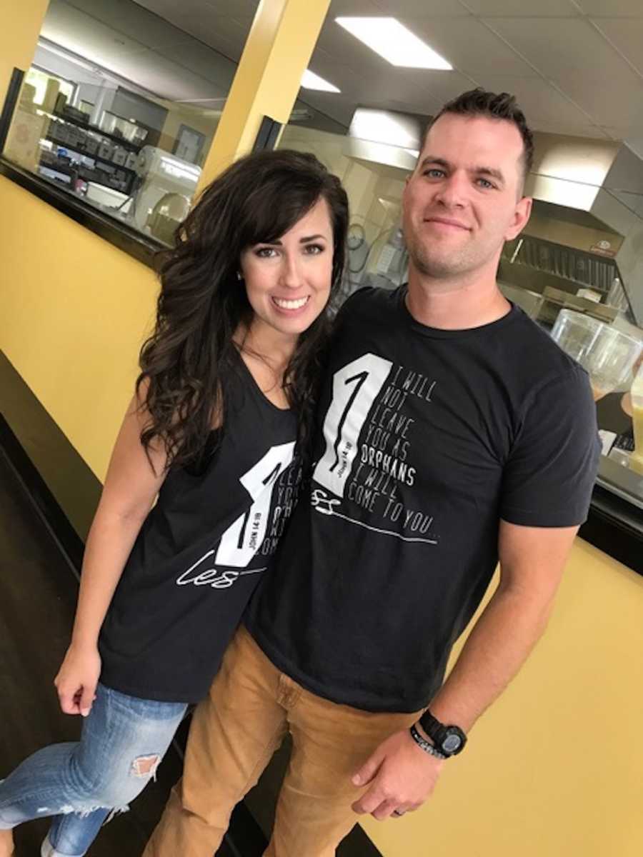 Husband and wife who wanted to adopt a child smile arm in arm in matching t-shirts