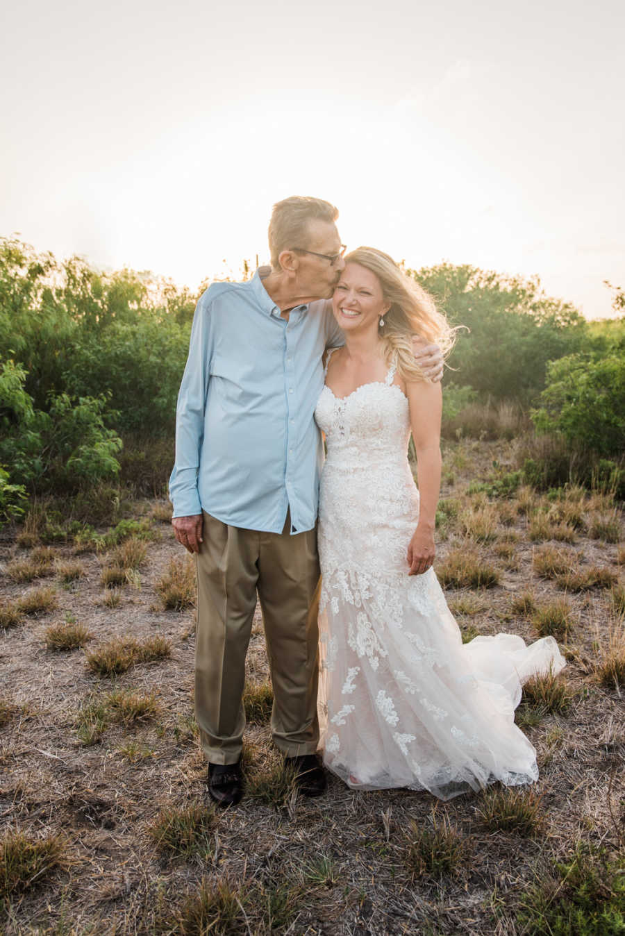 Father with cancer kisses head of daughter who is in her wedding gown