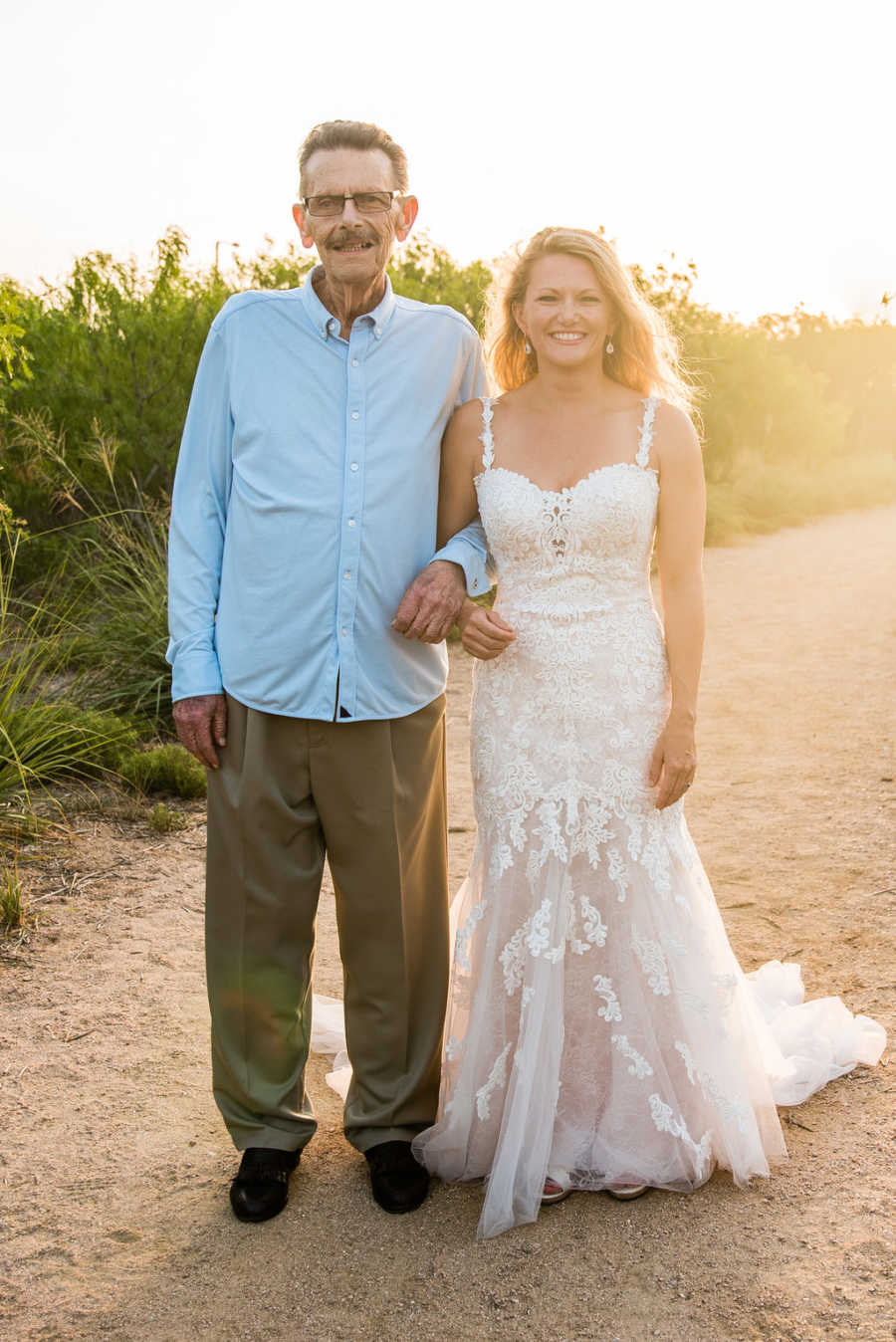 Woman in wedding gown stands arm in arm with father who was diagnosed with cancer