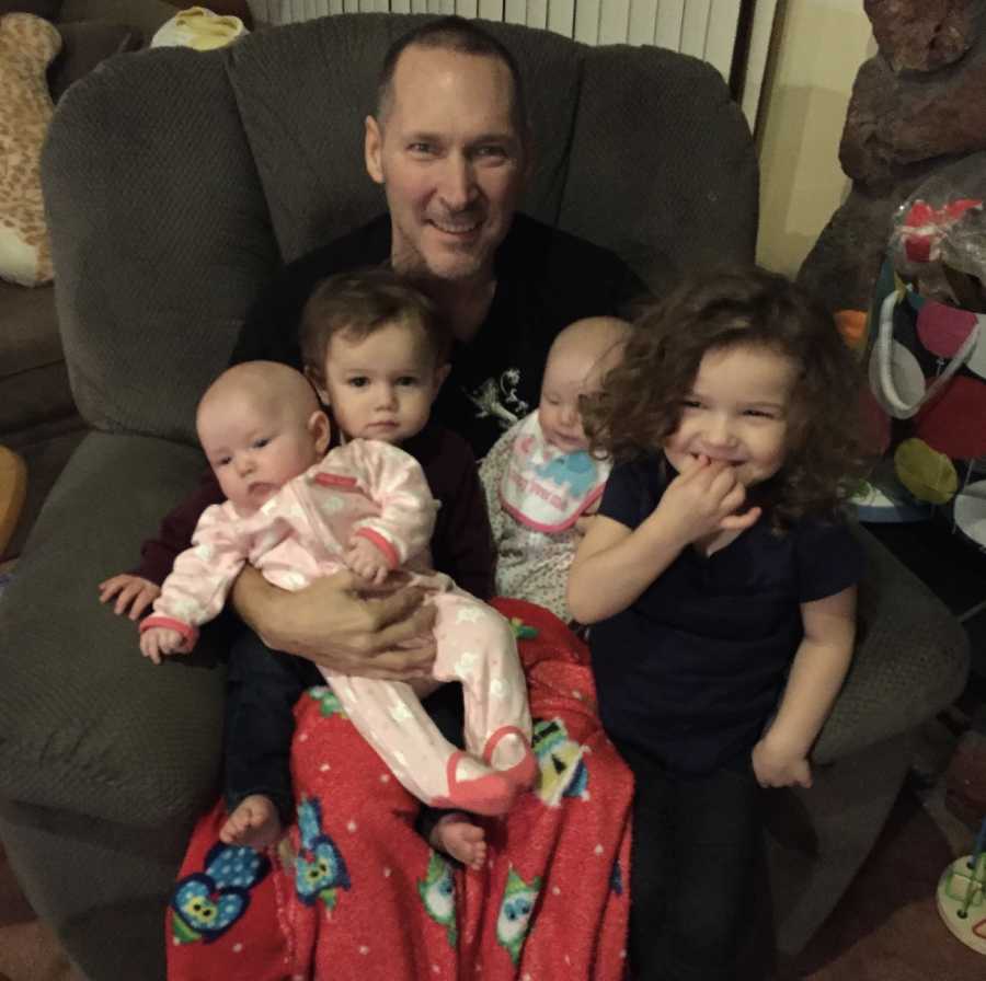 Grandfather sits in chair with four grandchildren in his lap