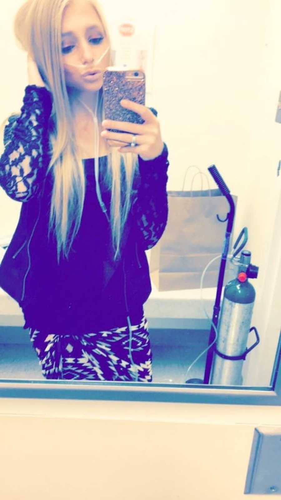 Woman with Cystic Fibrosis poses in mirror selfie with her oxygen tank