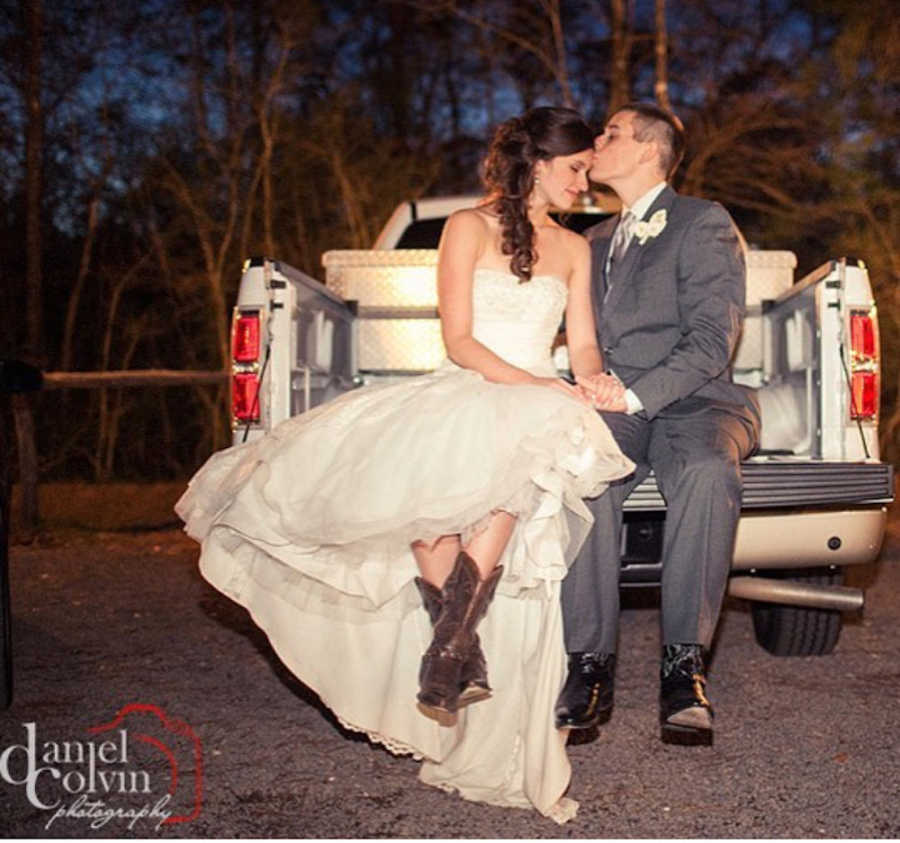 Bride and groom in cowboy boots sit in bed of truck