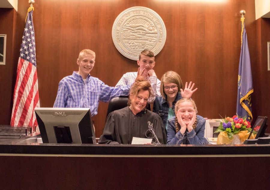 Judge sits behind the stand with four siblings who were just adopted in court