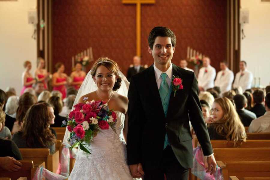 Bride and groom who will adopt a child smile as they walk down the aisle at their wedding