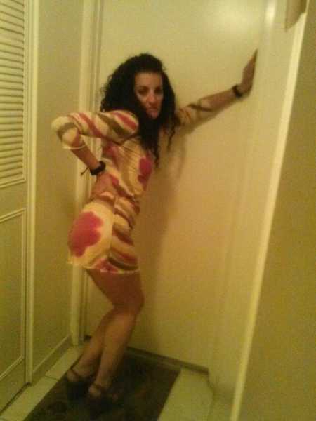 Woman who abuses alcohol and drugs poses in dress and heels with one hand on door and other on hip