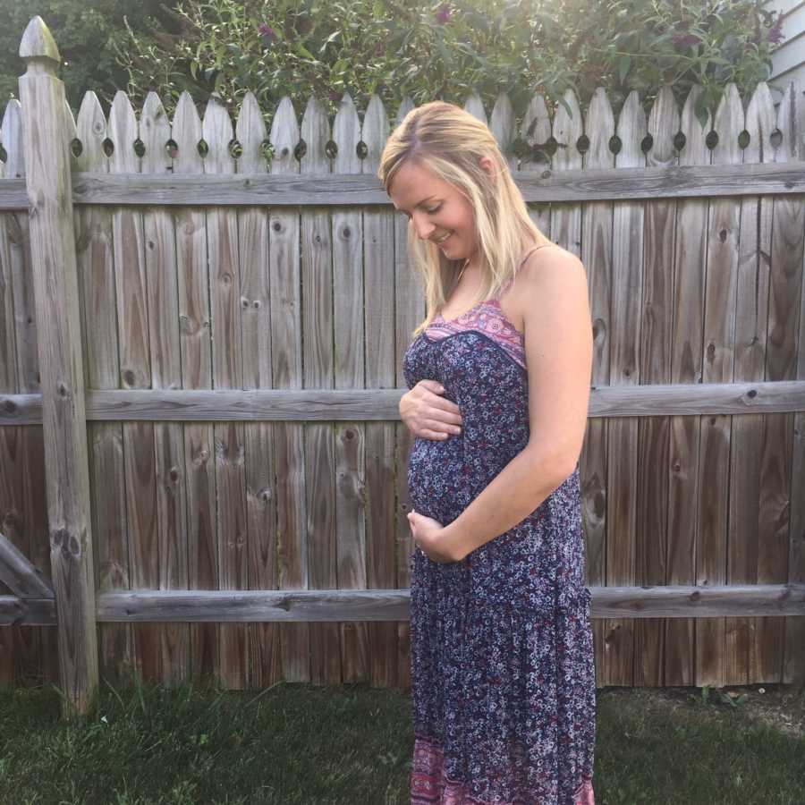 Pregnant woman holding her stomach and smiling after losing first born
