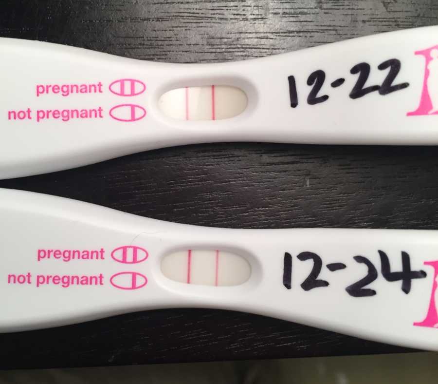 Two positive pregnancy tests with dates 12-22 and 12-24 written on them in black marker