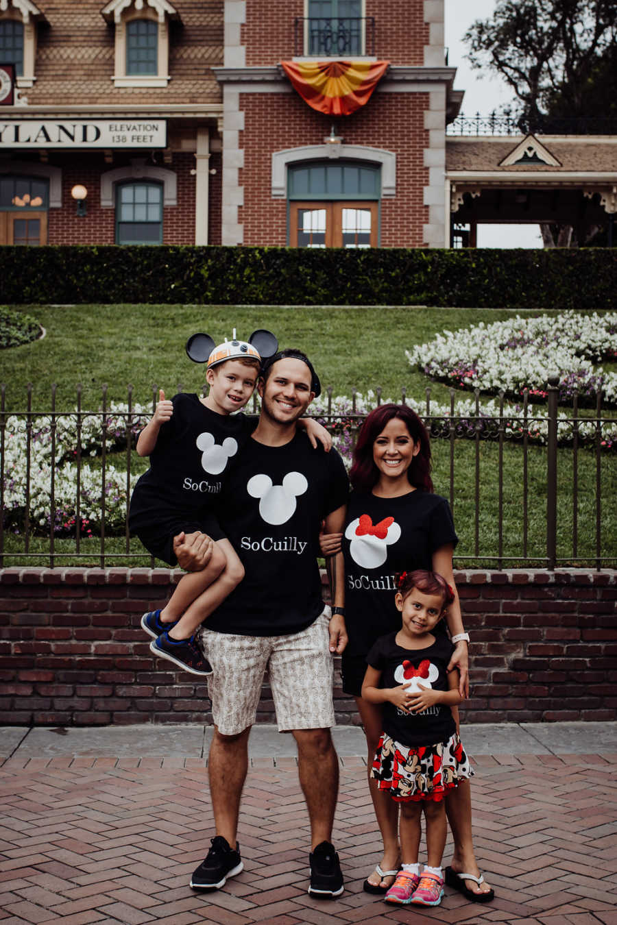 Mother and father stand with their son and daughter at Disney Land