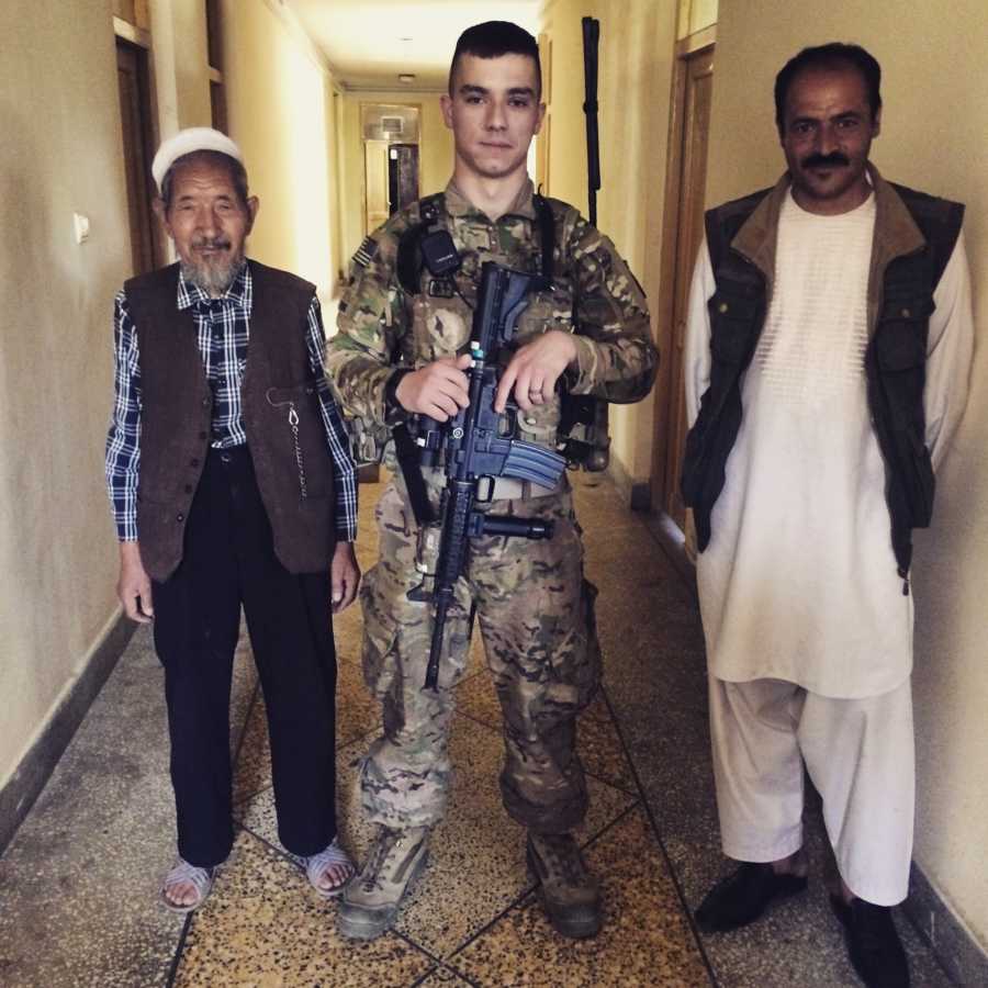 Soldier who used alcohol to deal with nerves stands with gun in Afghanistan next to locals
